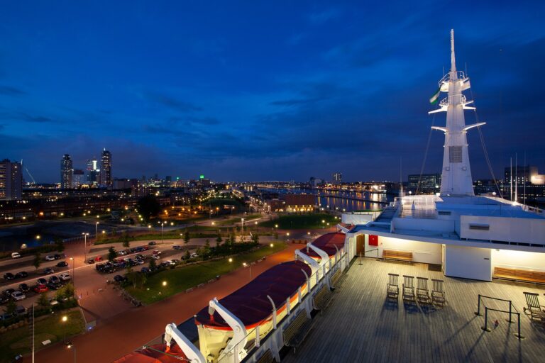 Uitzicht op de skyline van Rotterdam bij avond vanaf het dek van de SS Rotterdam