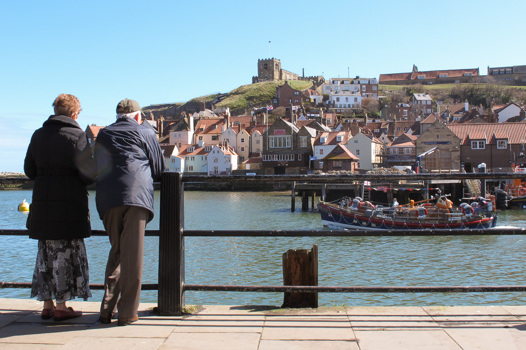 Mensen in de haven van Whitby, met Whitby Abbey in de verte